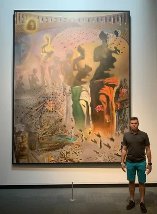 Frank Castro standing in front of Salvador Dalí's painting "The Hallucinogenic Toreador"